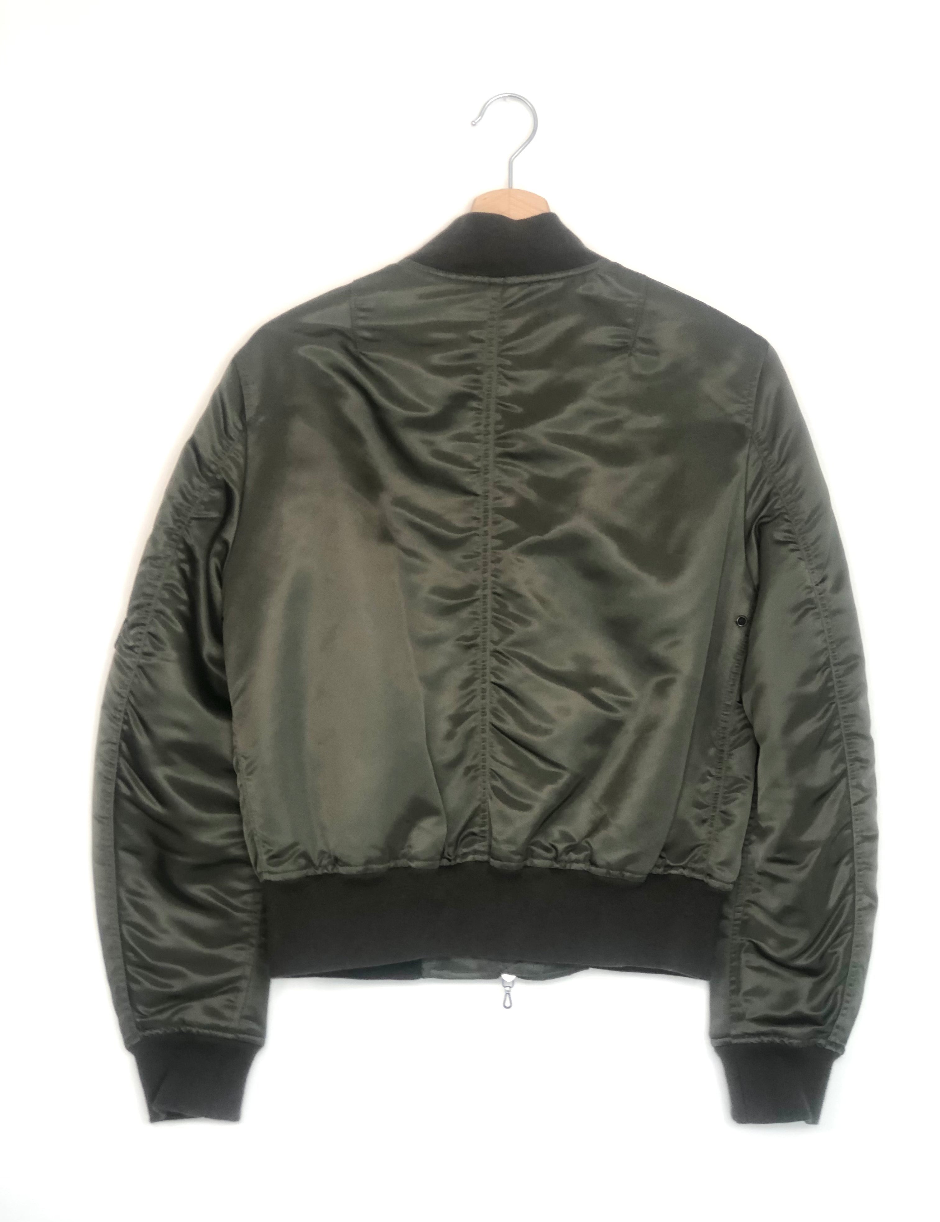 Green bomber jacket on a hanger against a white background