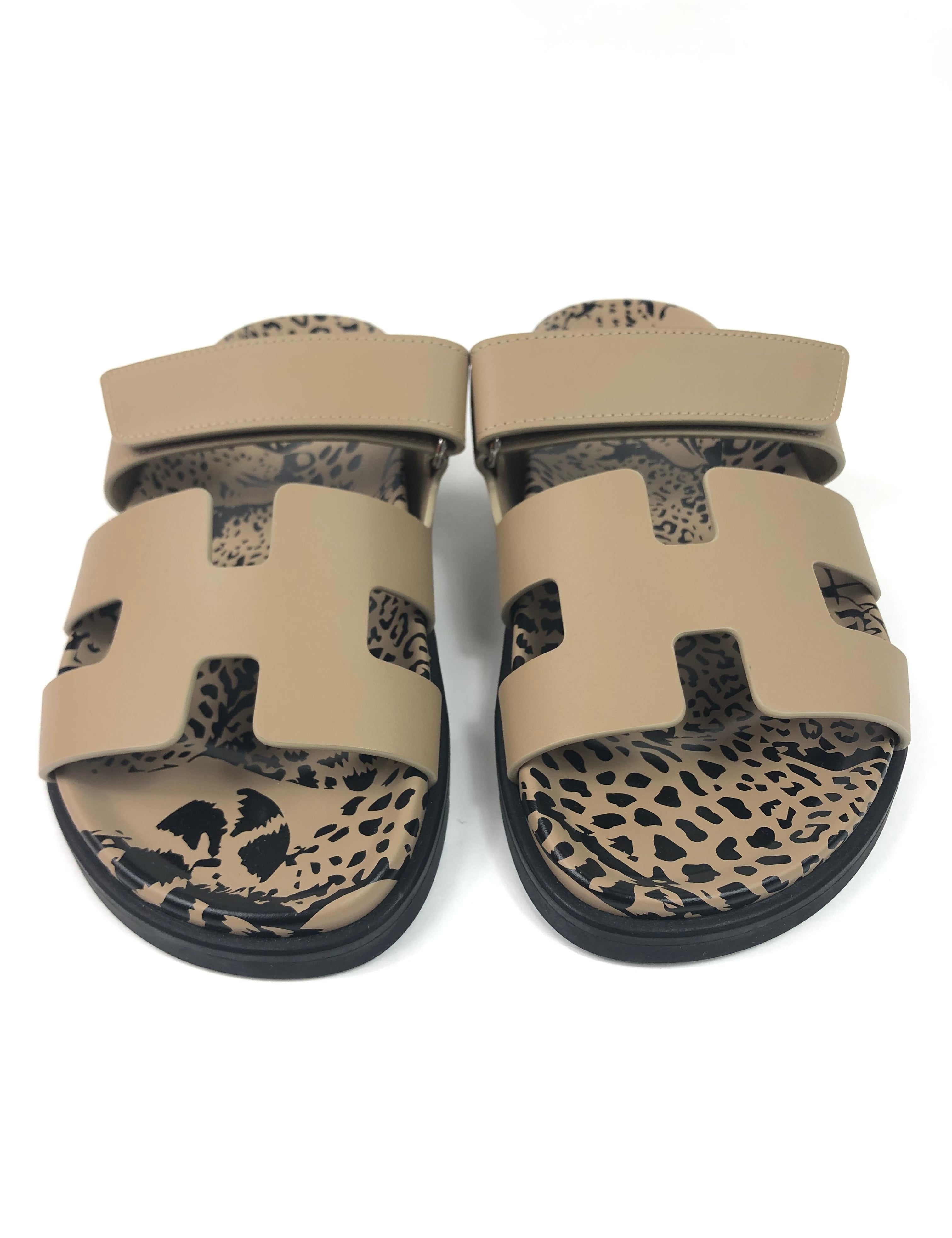 Pair of beige sandals with leopard print soles on a white background