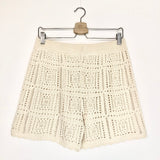 Beige crochet shorts on a hanger against a white background