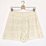 Beige crochet skirt on a hanger against a white background