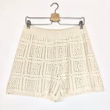 Beige crochet skirt on a hanger against a white background