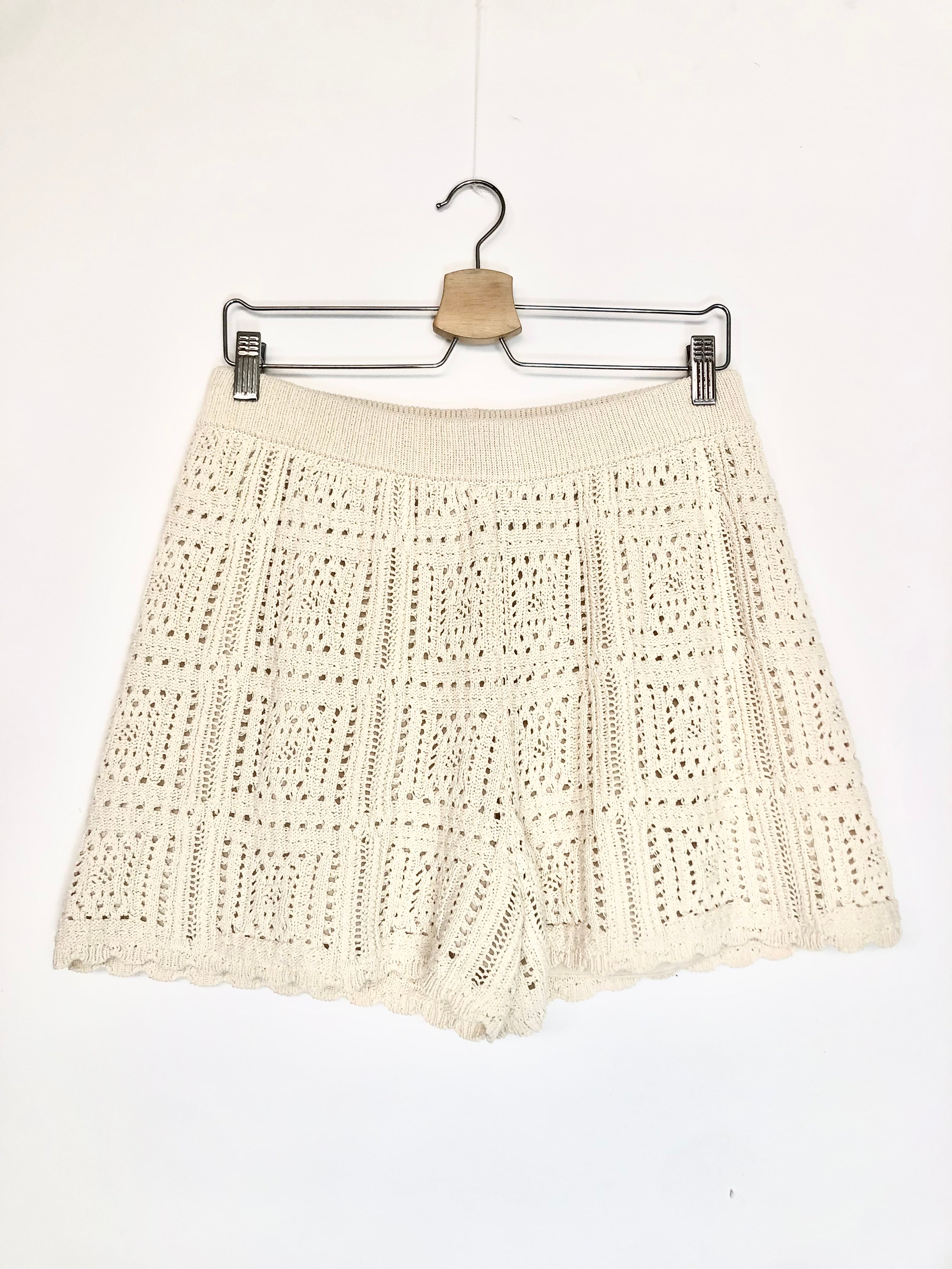 Beige crochet skirt on a hanger against a white background