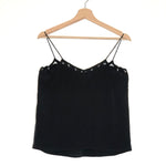 Black spaghetti strap top on a wooden hanger against a white background