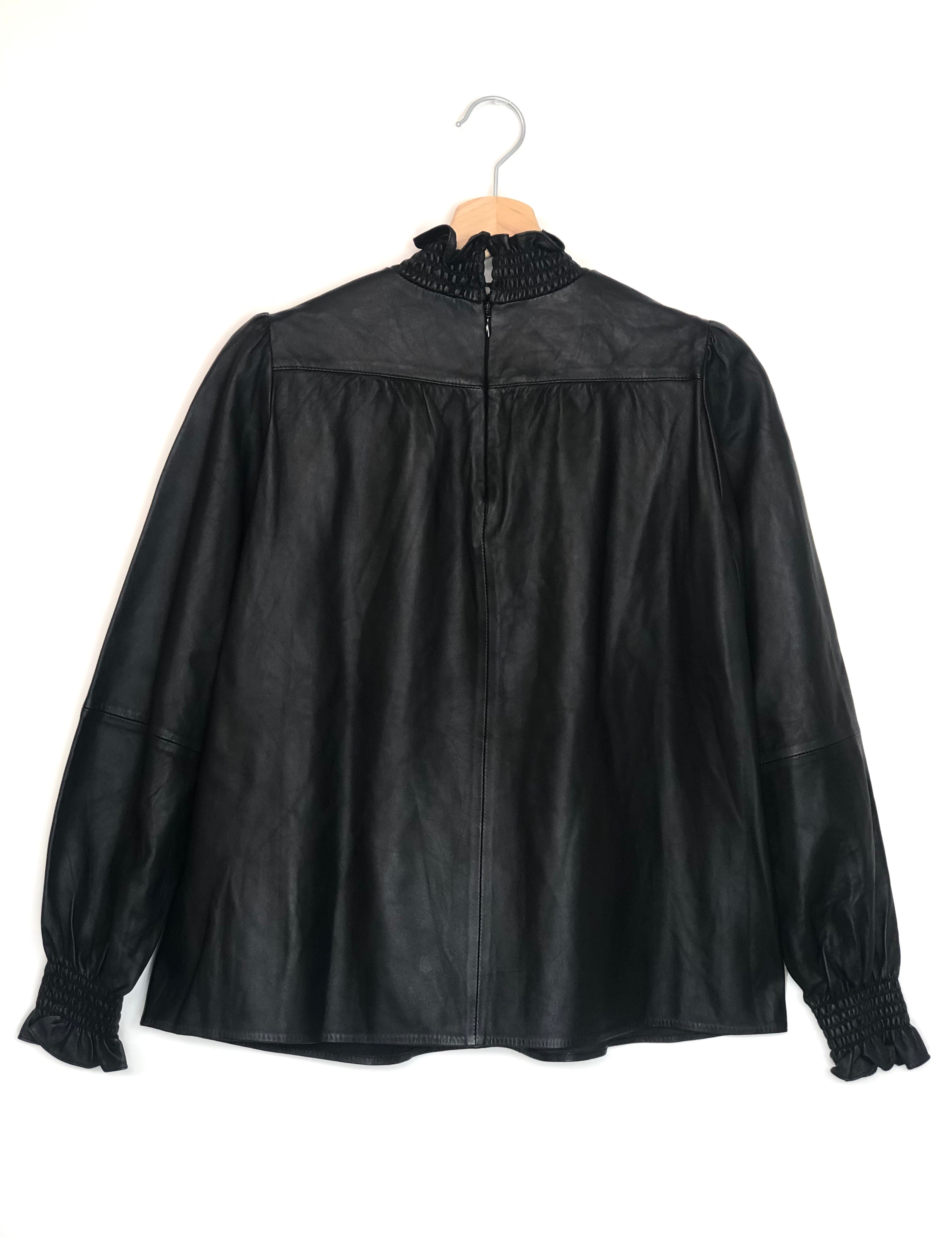 Black leather blouse on a hanger against a white background
