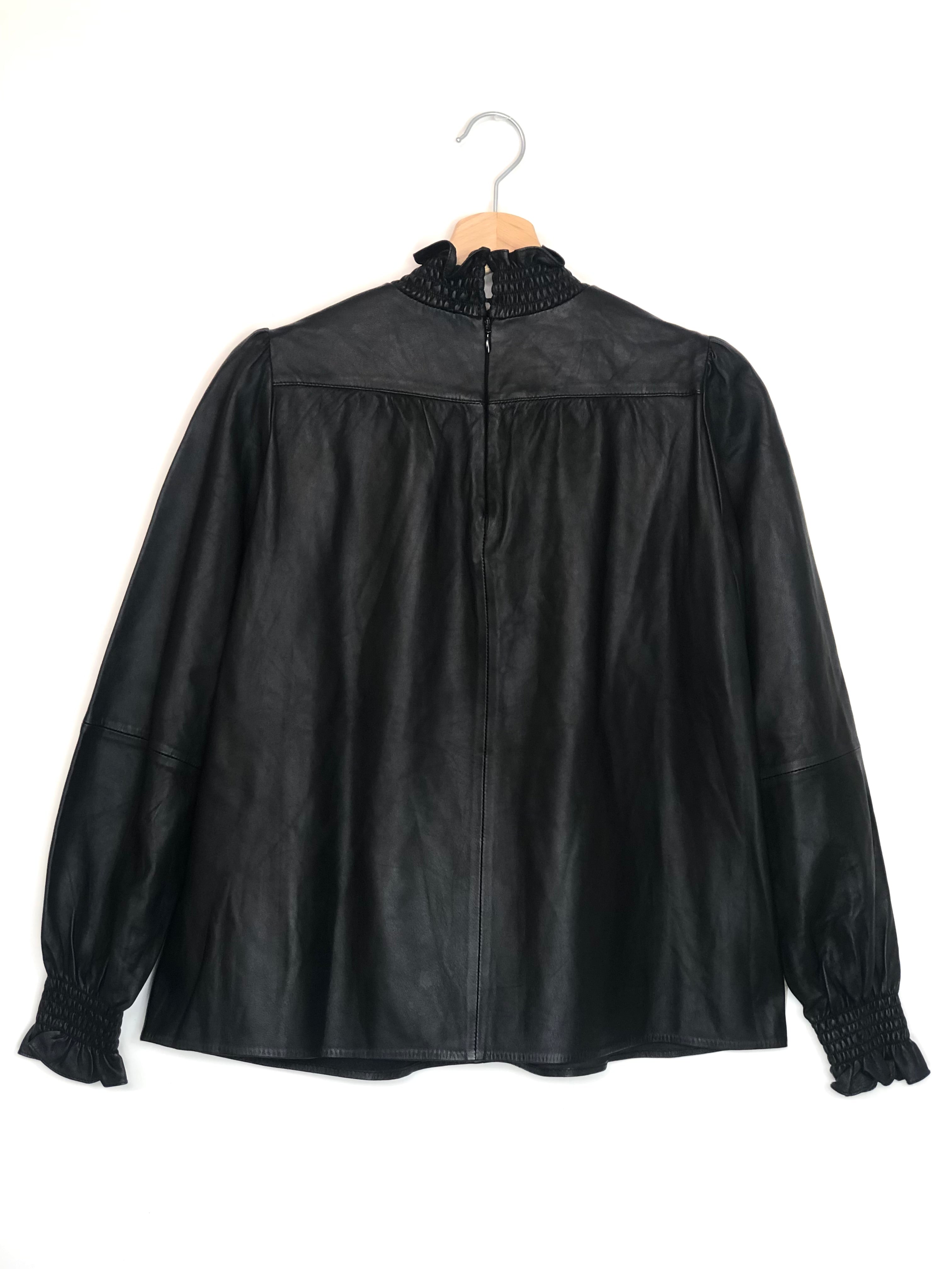 Black leather blouse on a hanger against a white background