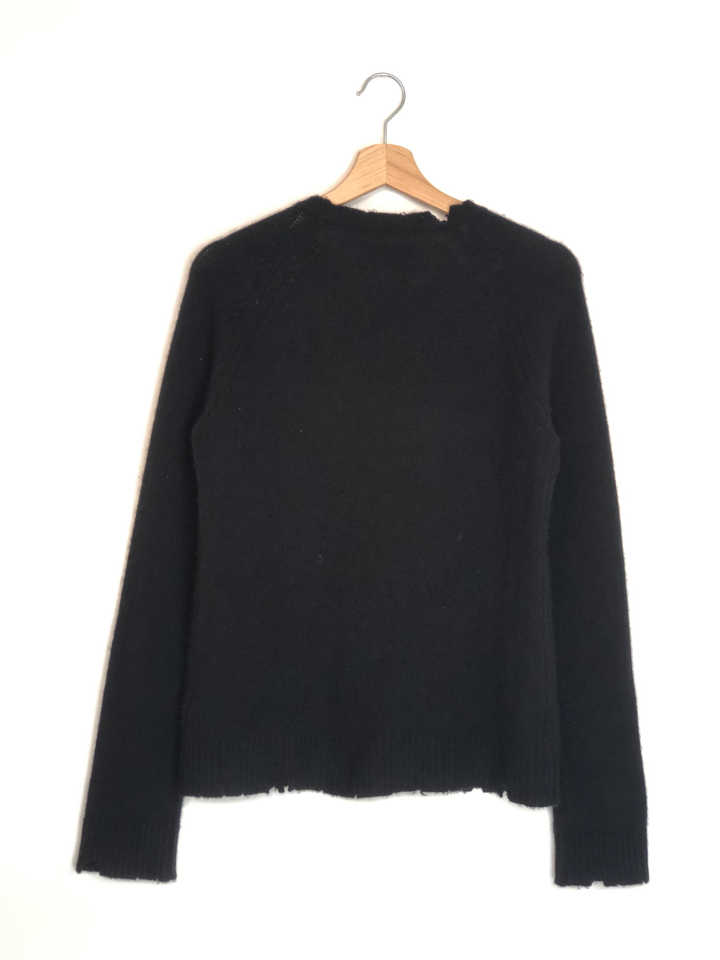 Black sweater on a hanger against a white background