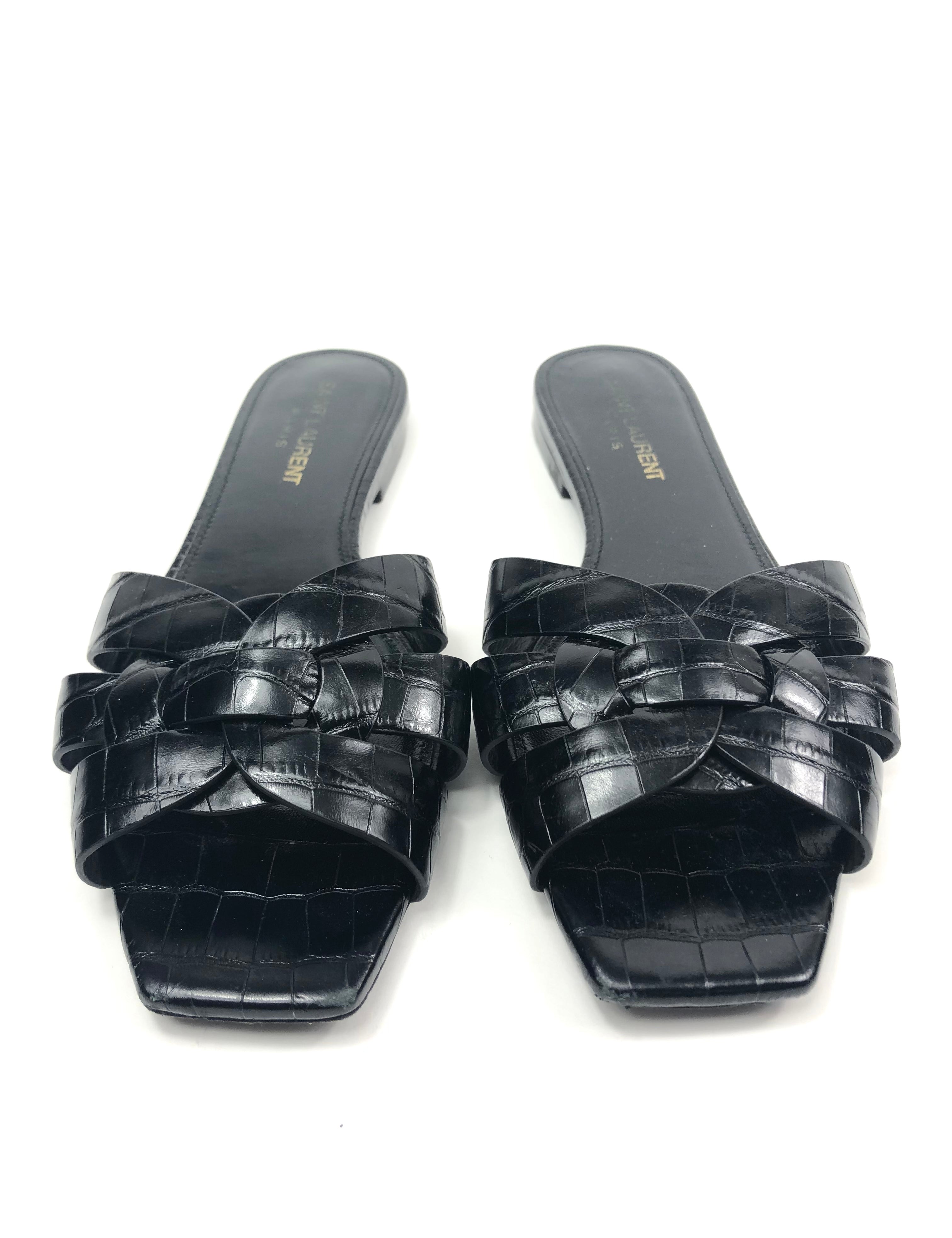 Pair of black woven sandals on a white background