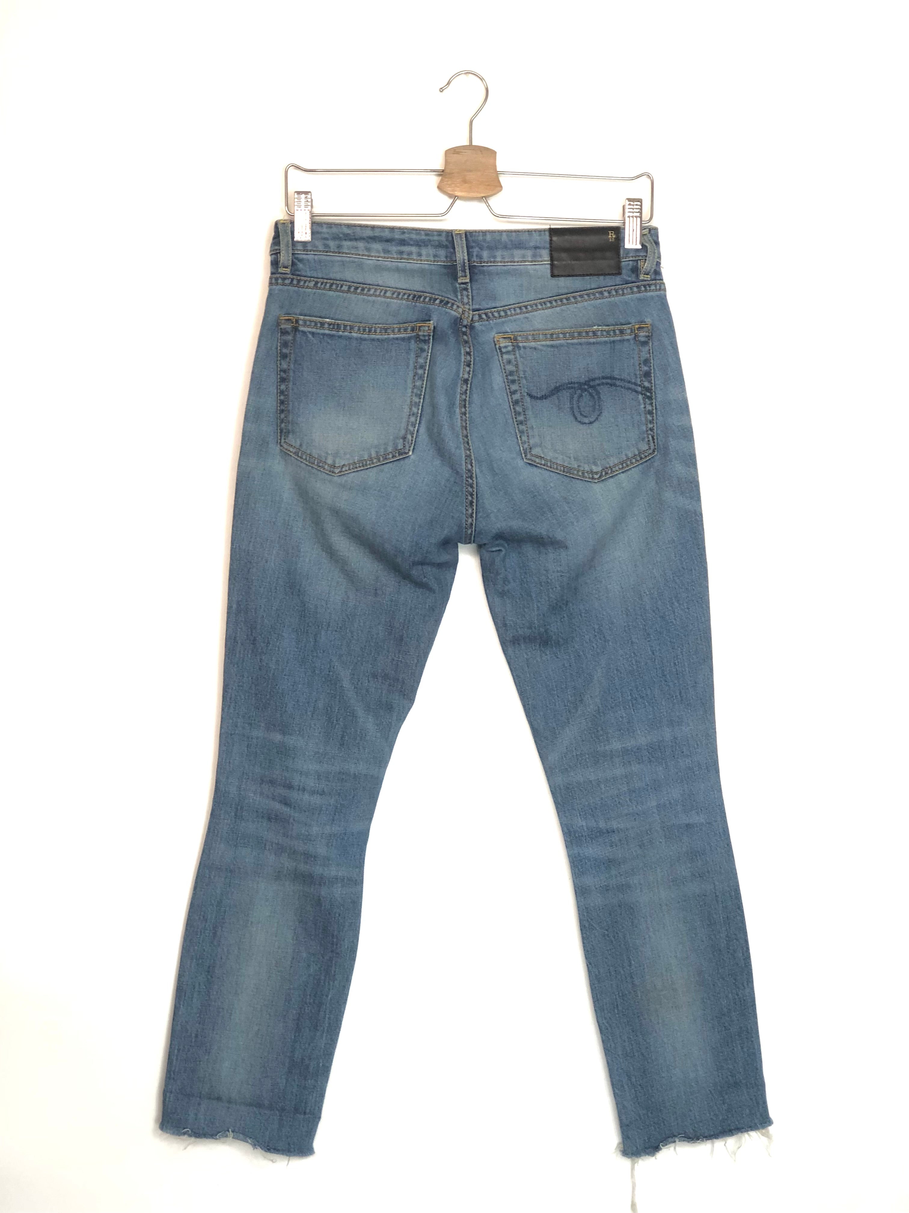 Blue jeans on a hanger against a white background