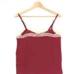 Red lace-trimmed camisole on a wooden hanger against a white background