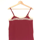 Red lace-trimmed camisole on a wooden hanger against a white background