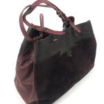 Brown leather handbag with a black section on a white background