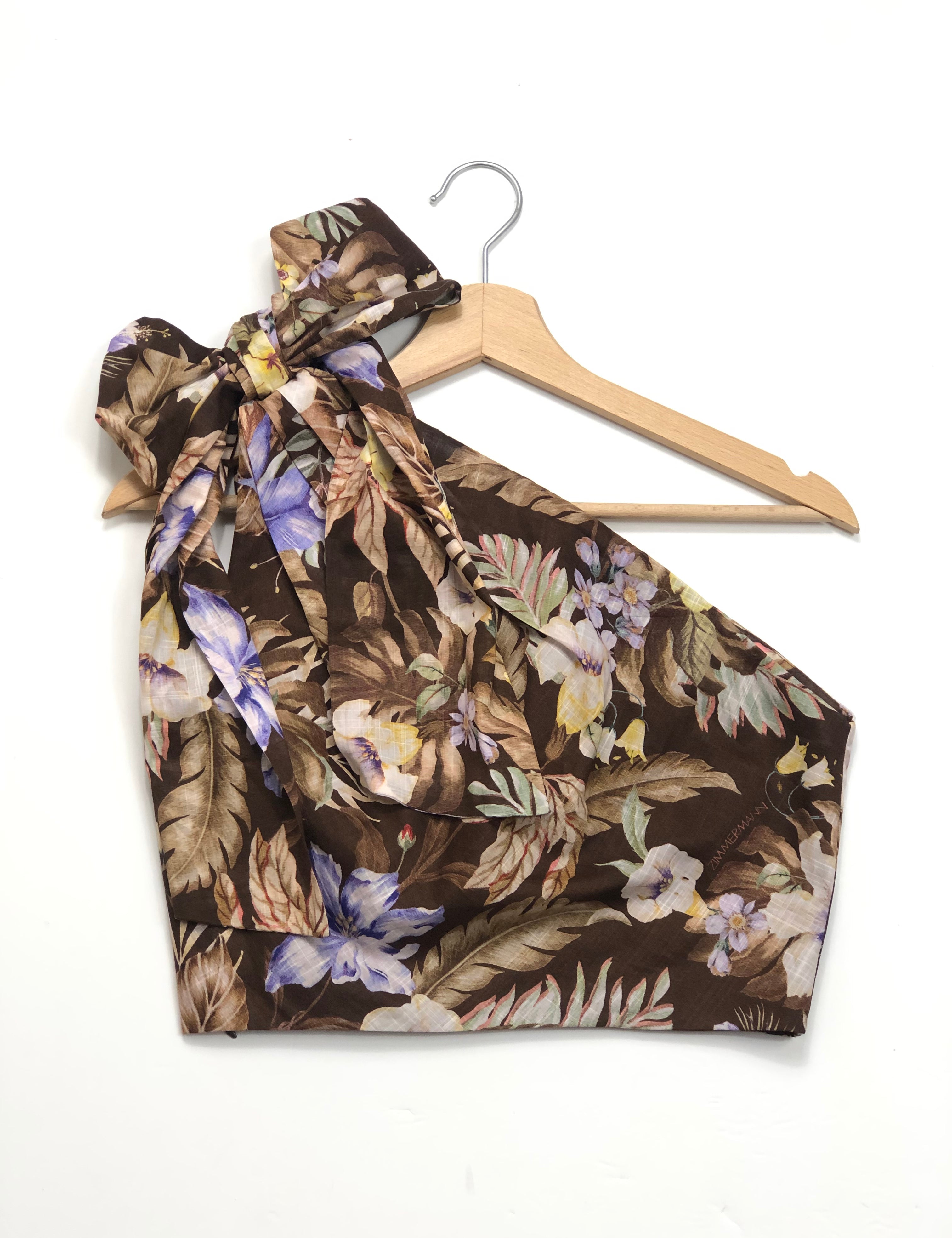 Floral-patterned top on a hanger against a white background