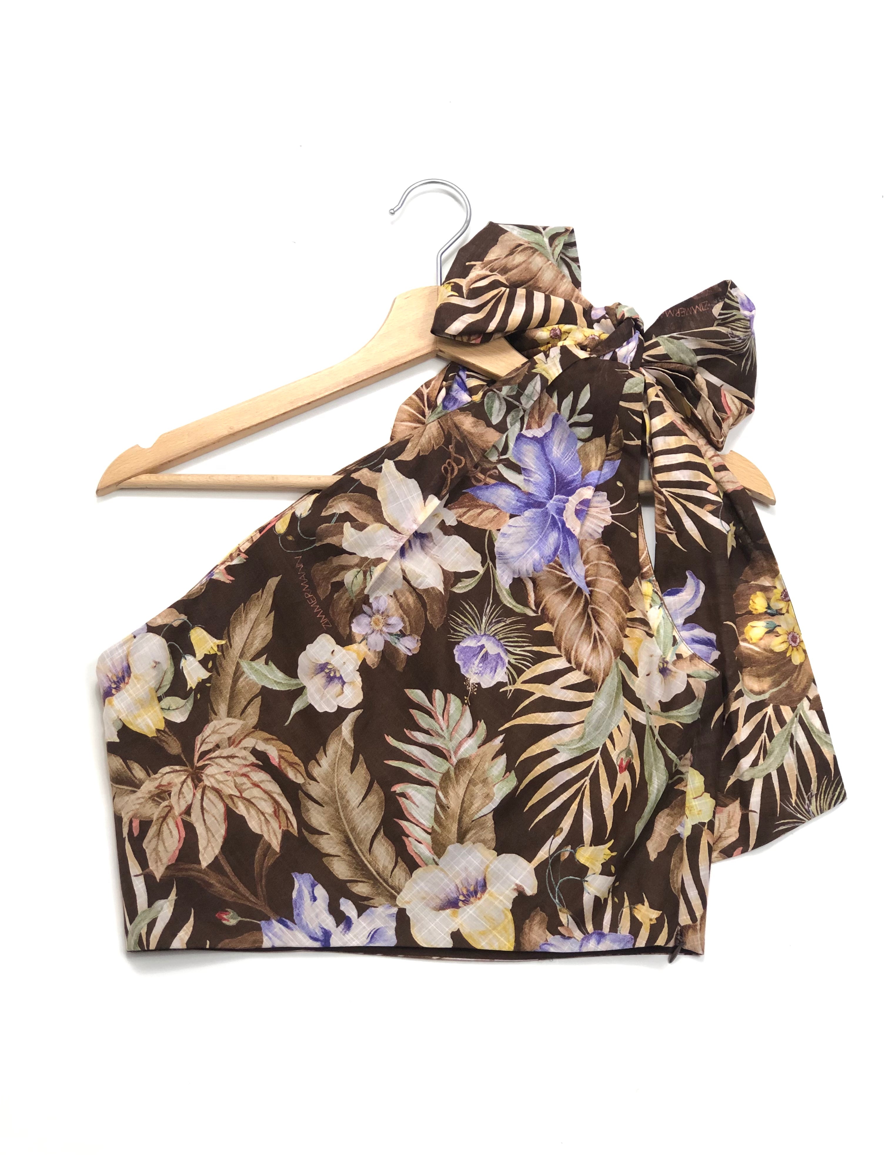 Floral halter top on a wooden hanger against a white background
