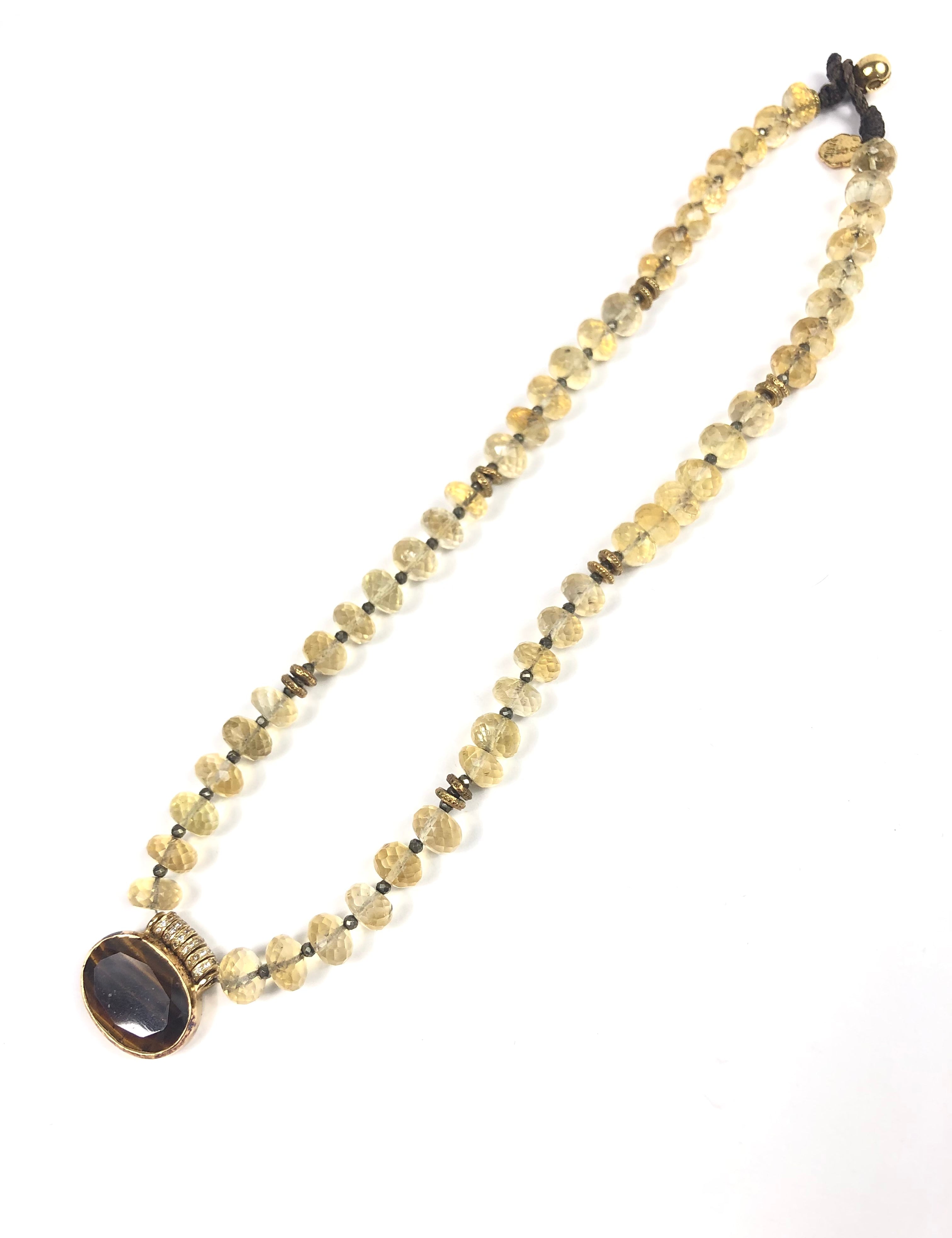 Necklace with beaded chain and dark pendant on a white background