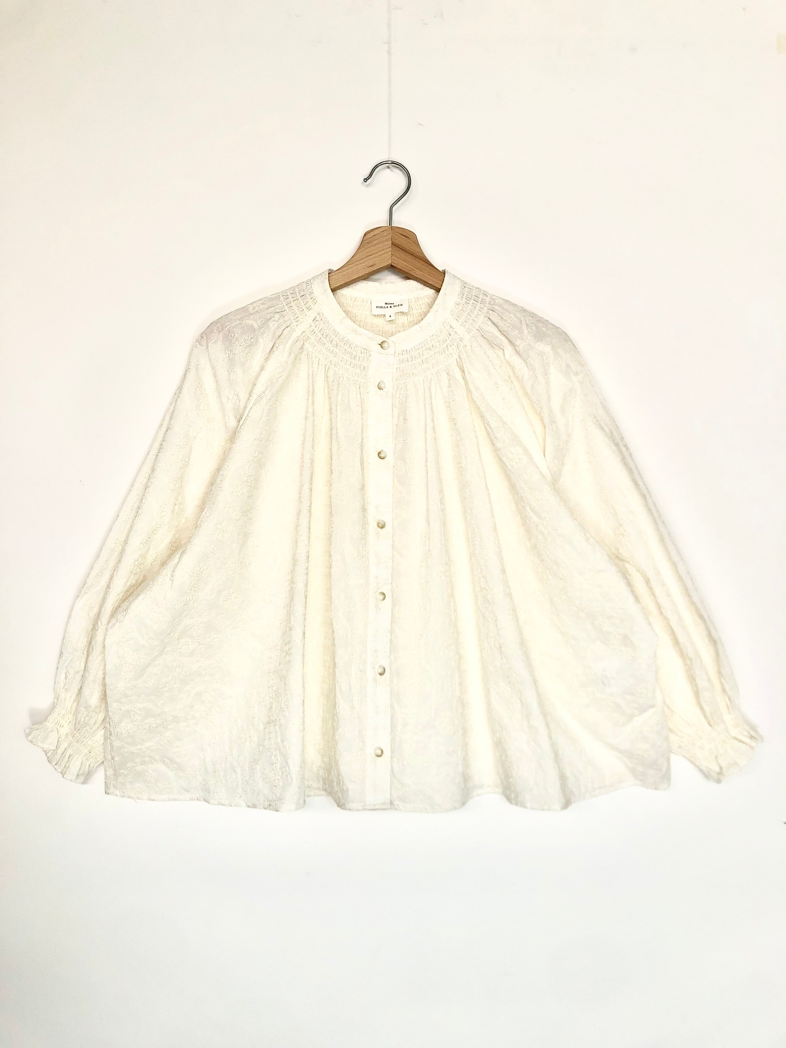 White blouse on a hanger against a white background