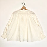 White lace blouse on a wooden hanger against a white background