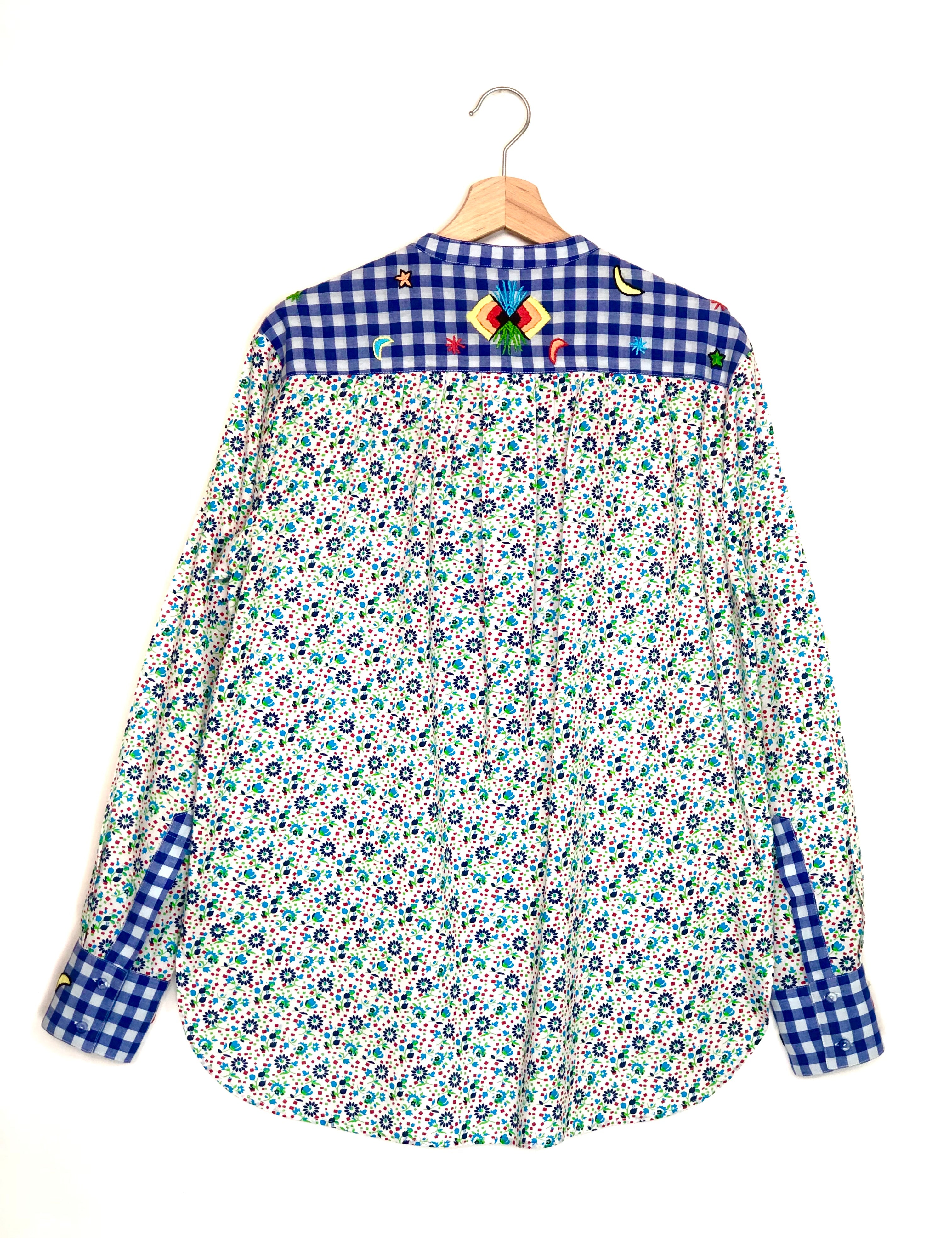 Floral shirt with checkered collar and sleeves on a hanger against a white background