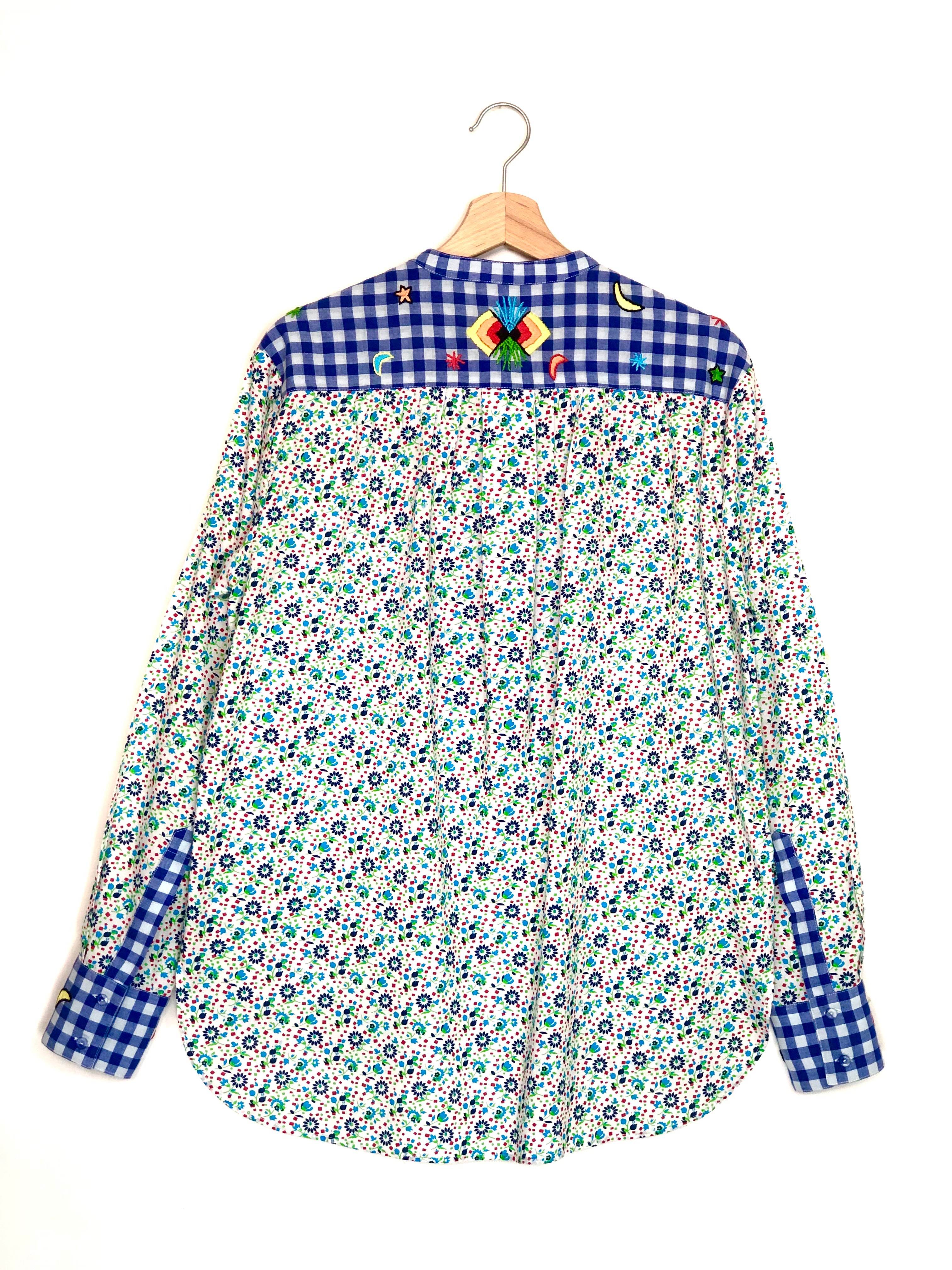 Floral shirt with checkered collar and sleeves on a hanger against a white background