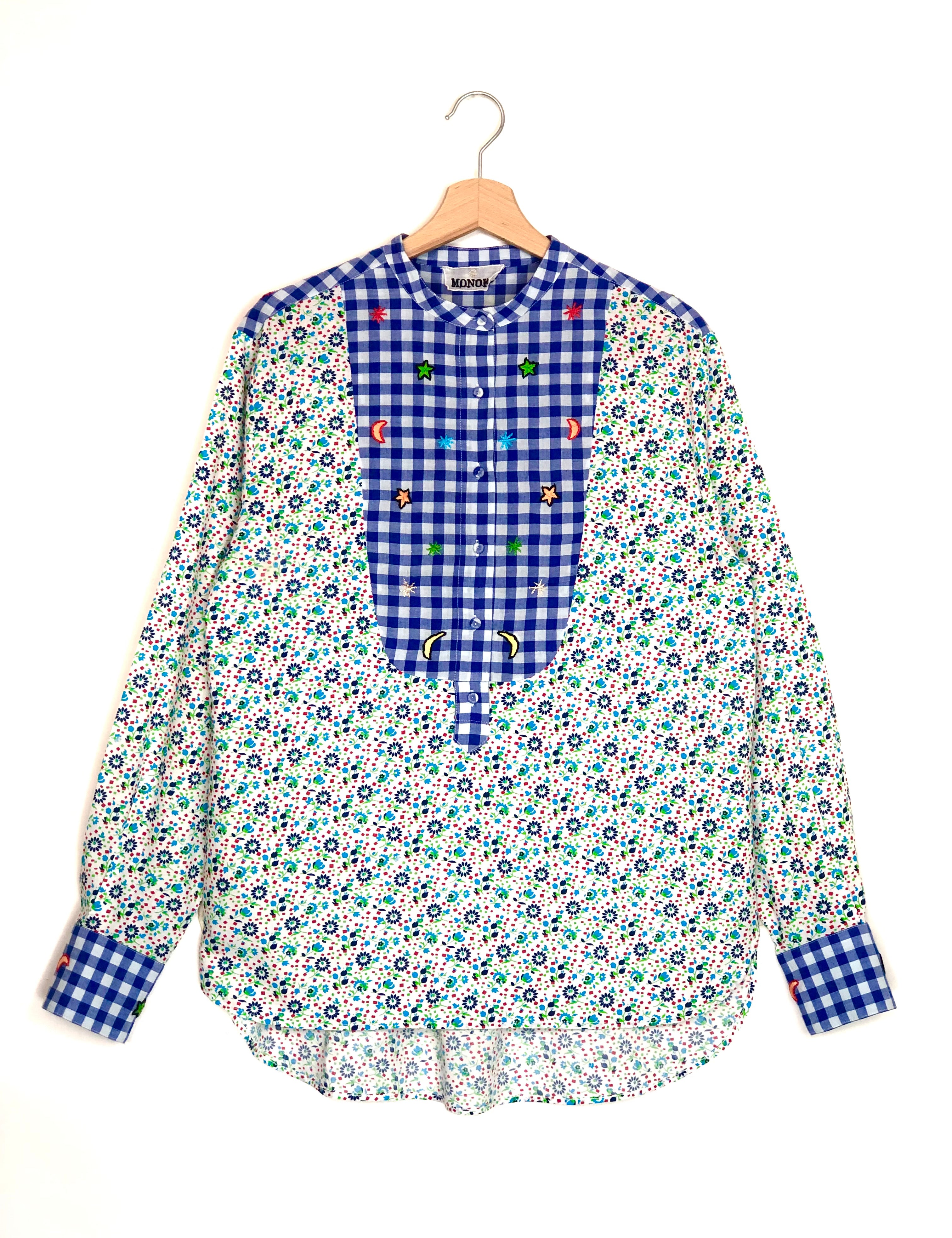 Floral and checkered blouse on a hanger against a white background