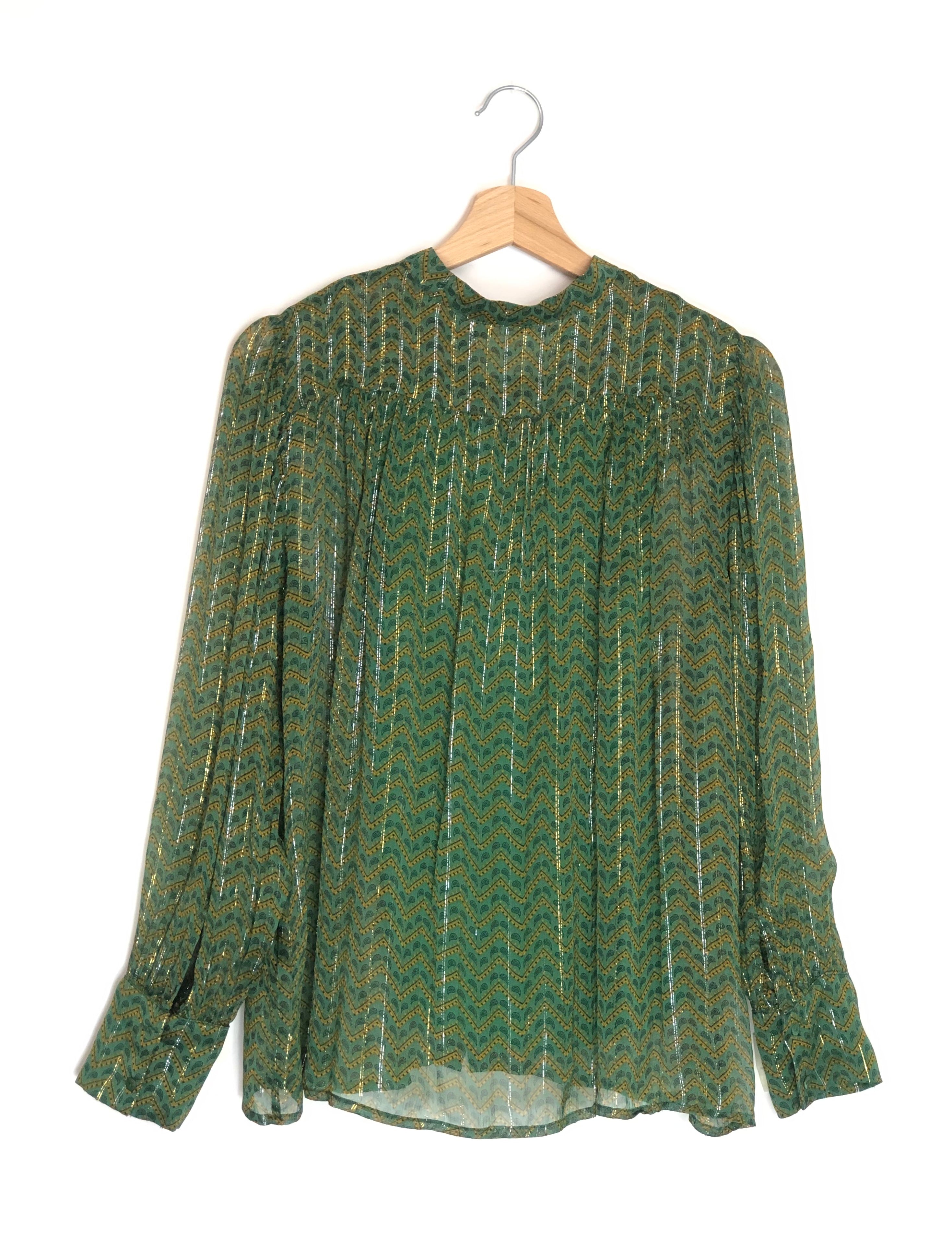 Green patterned blouse on a wooden hanger against a white background