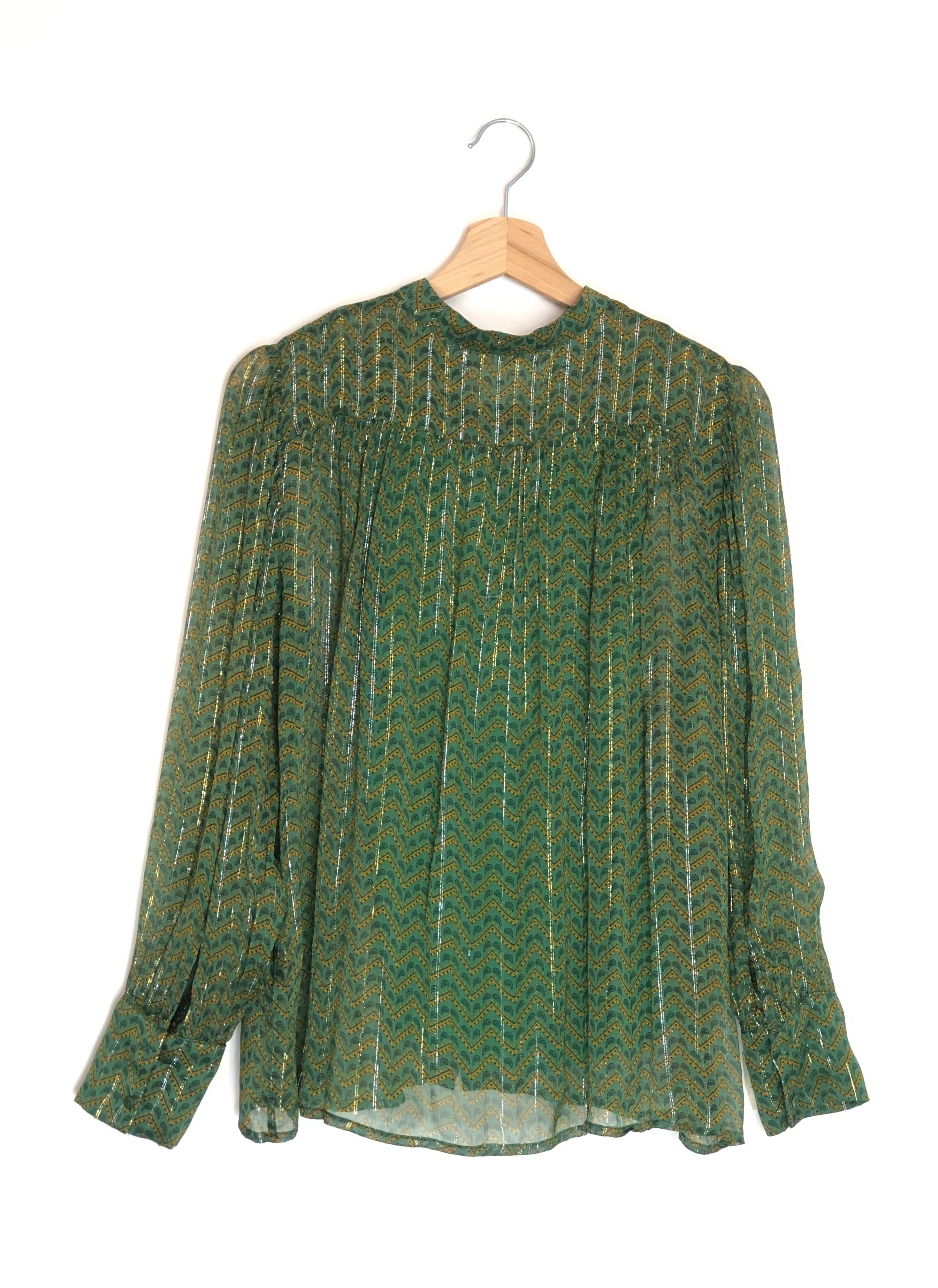 Green patterned blouse on a wooden hanger against a white background