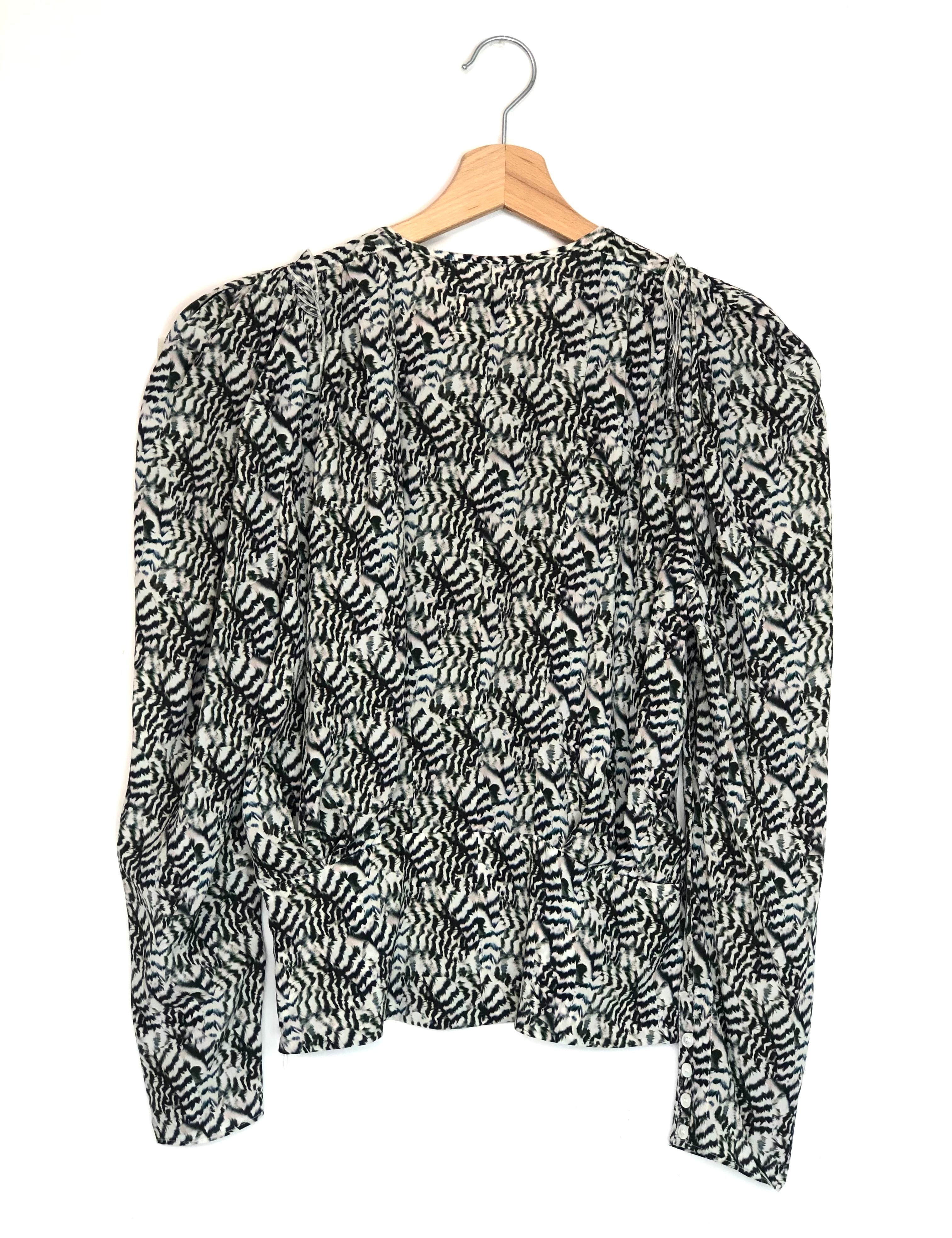 Black and white patterned blouse on a hanger against a white background