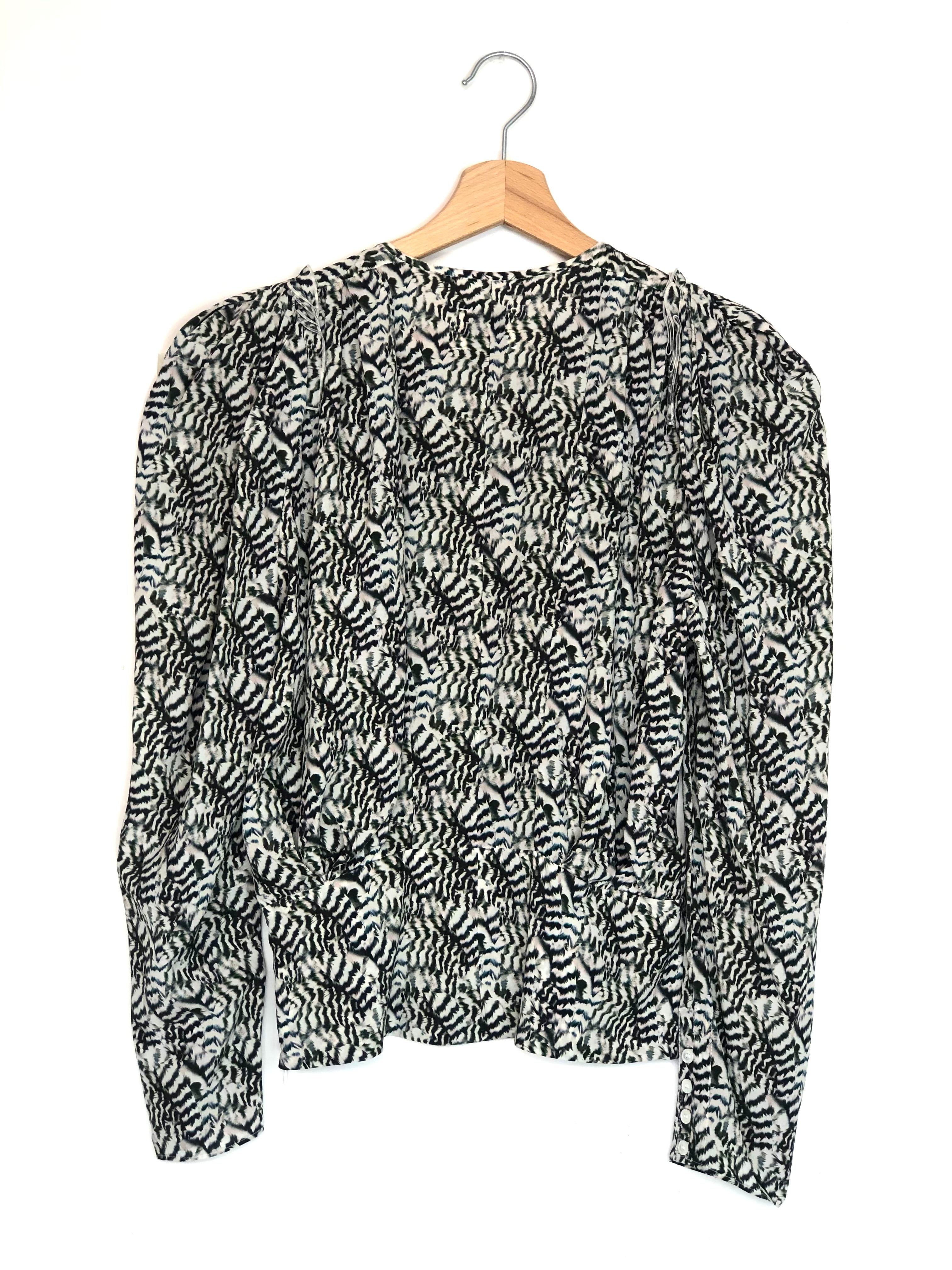 Black and white patterned blouse on a hanger against a white background