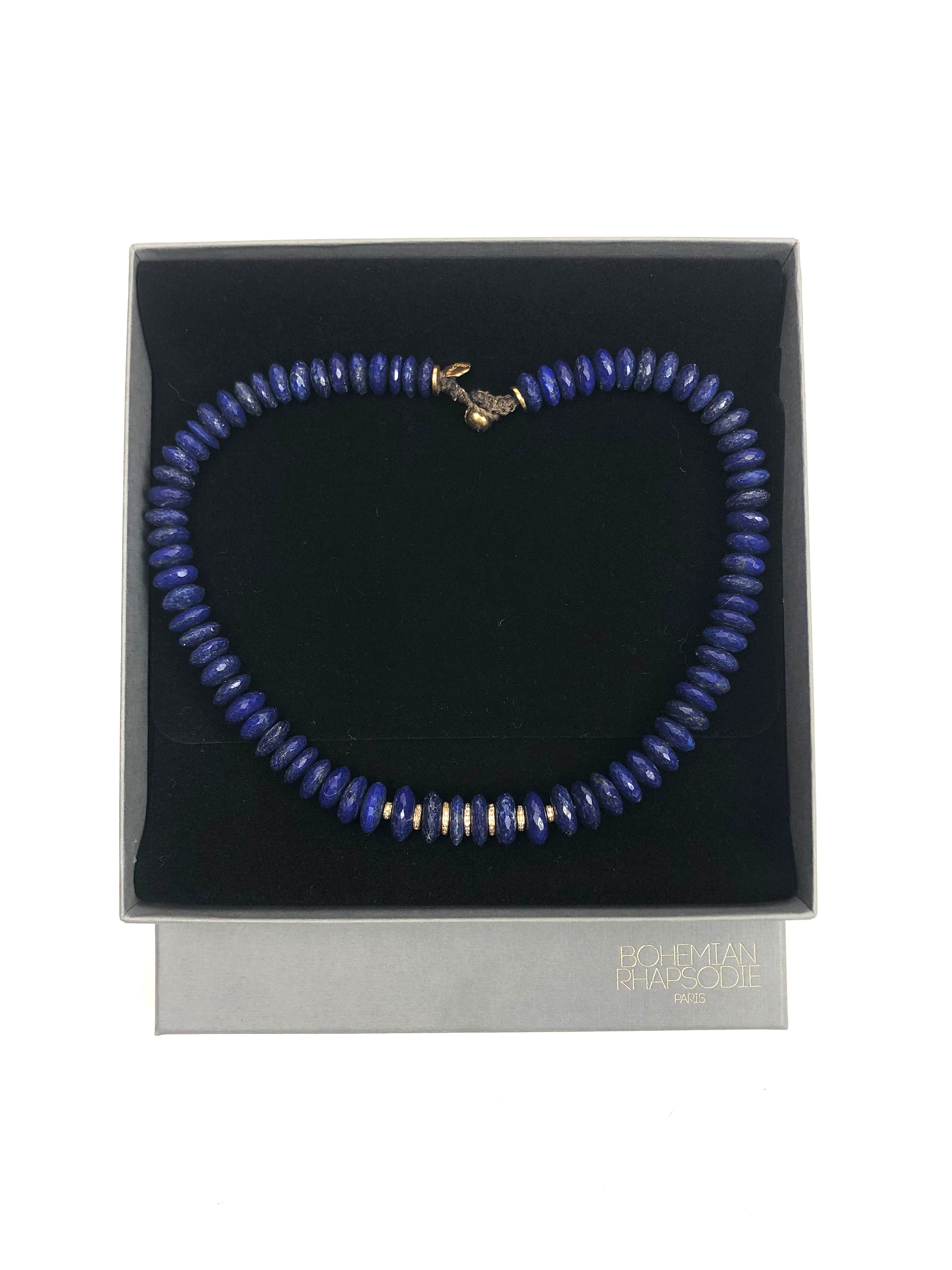 Blue beaded necklace on a black display card with a brand name, against a white background