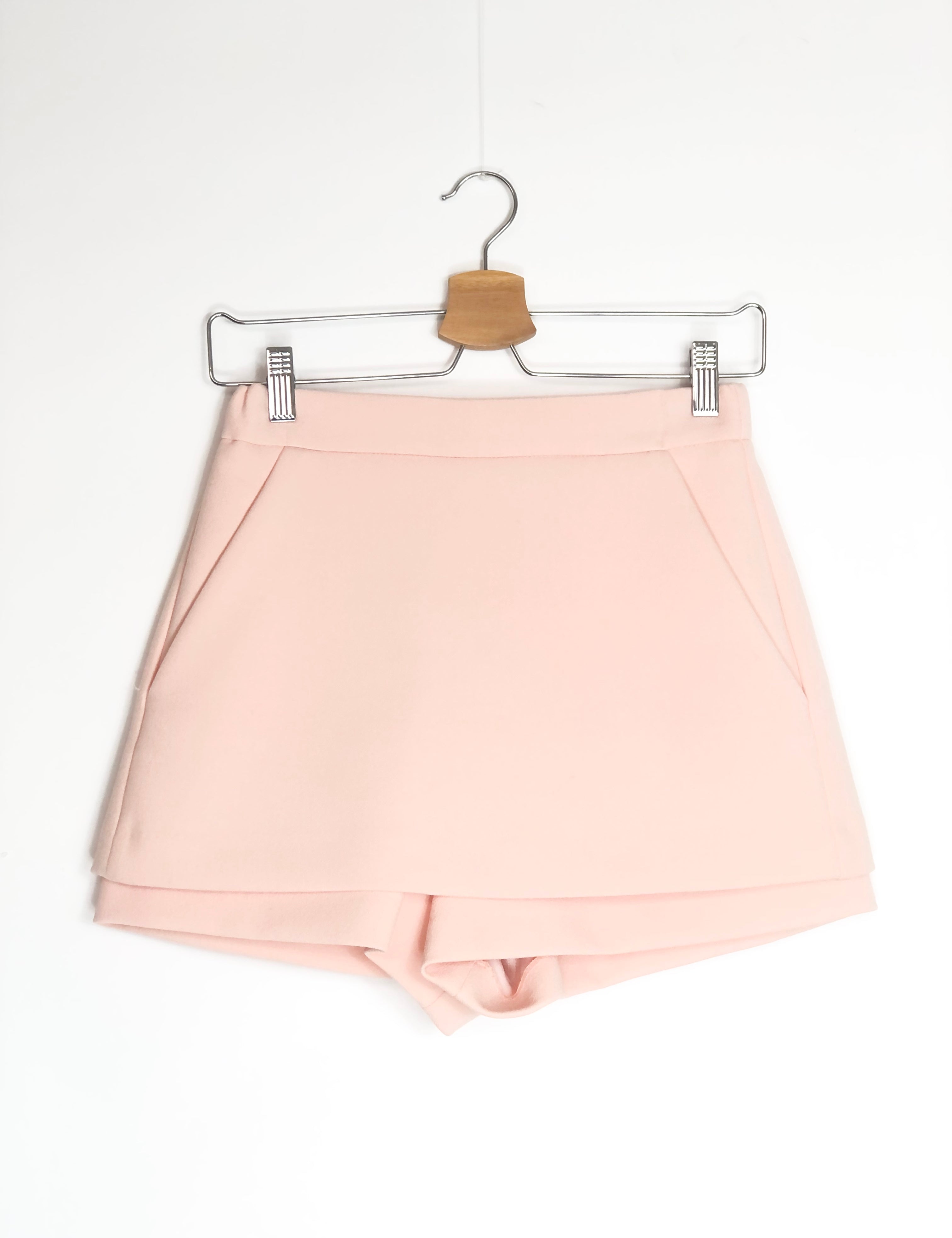 Light pink shorts on a hanger against a white background