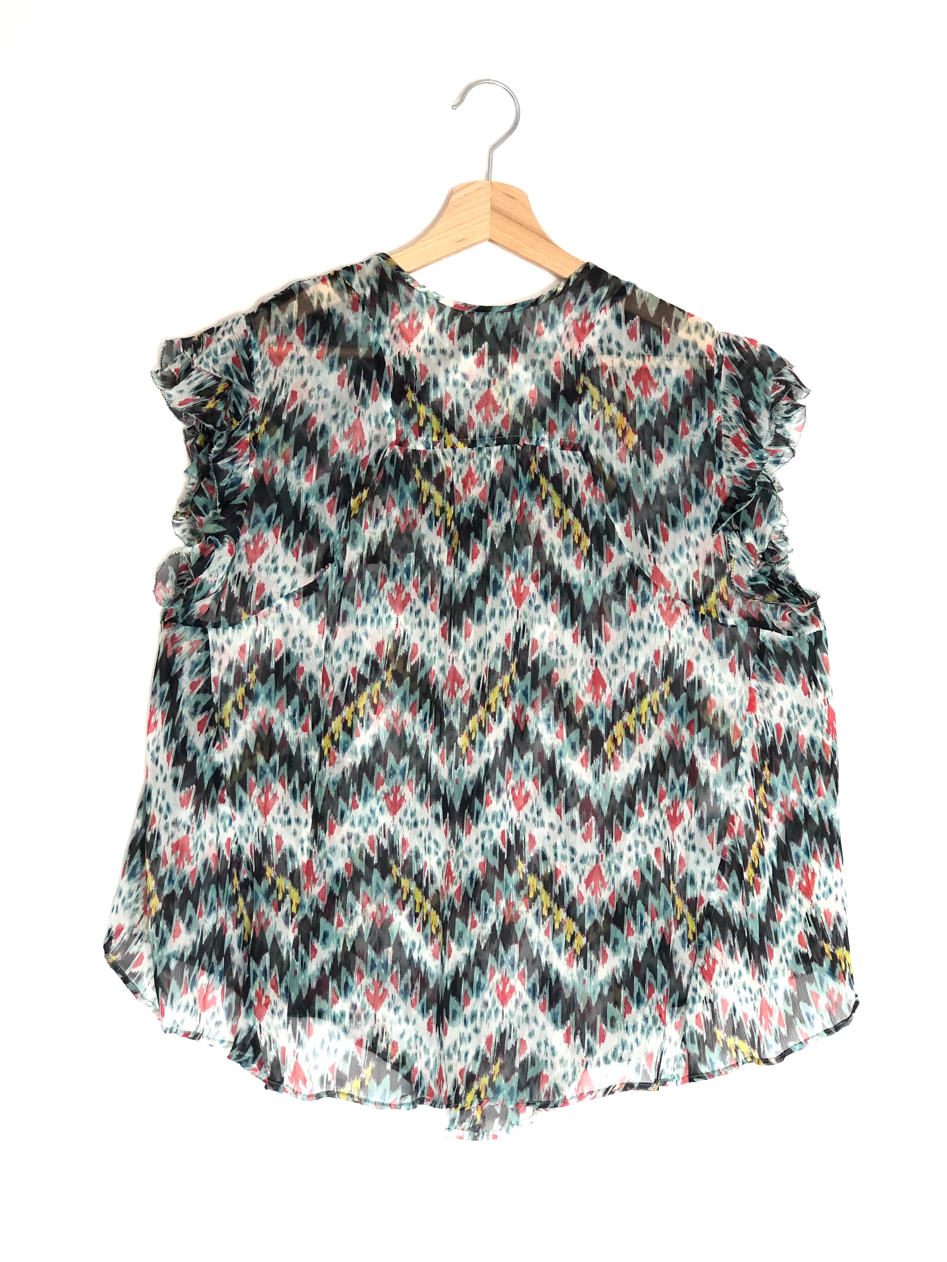 Floral and zigzag patterned top on a hanger against a white background
