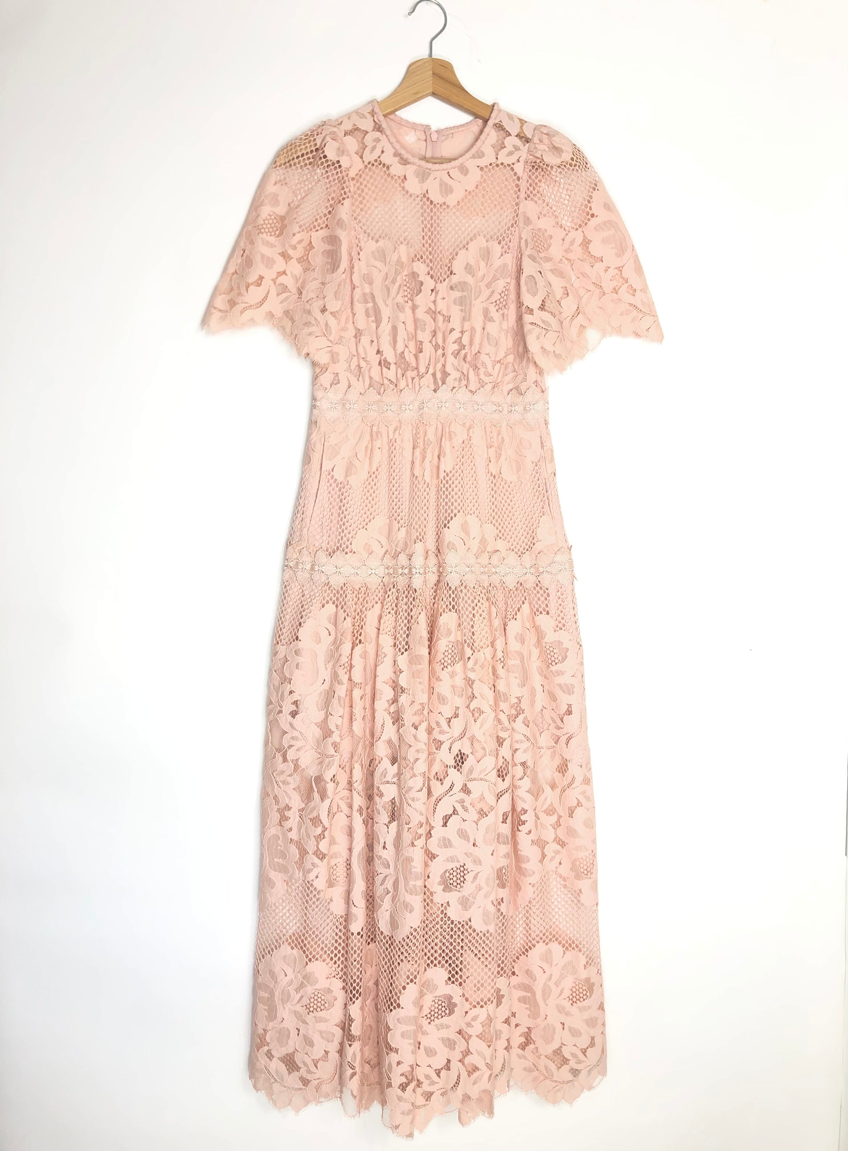 Pink lace dress on a hanger against a white background