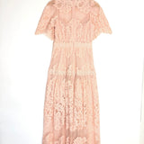 Pink lace dress on a hanger against a white background
