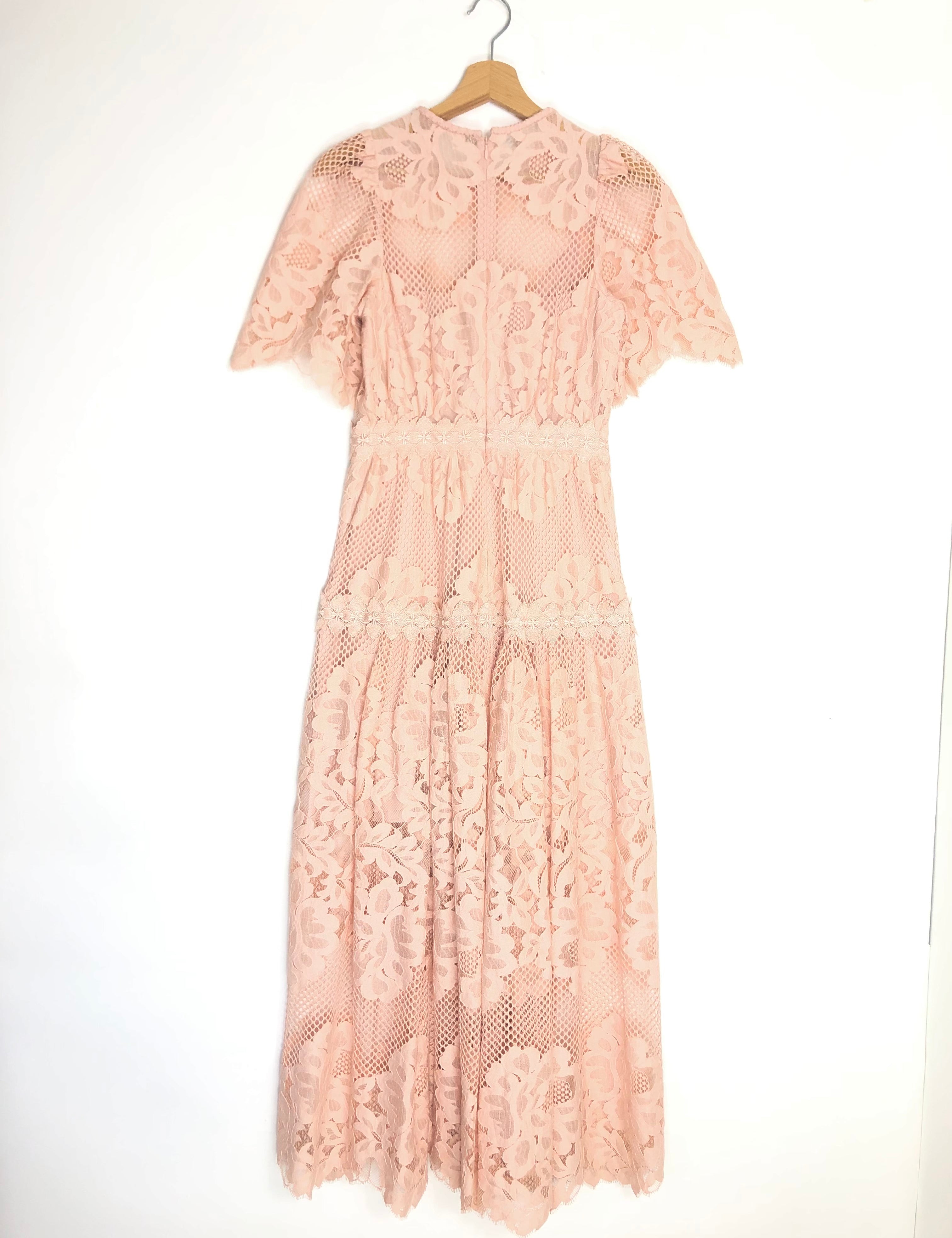 Pink lace dress on a hanger against a white background