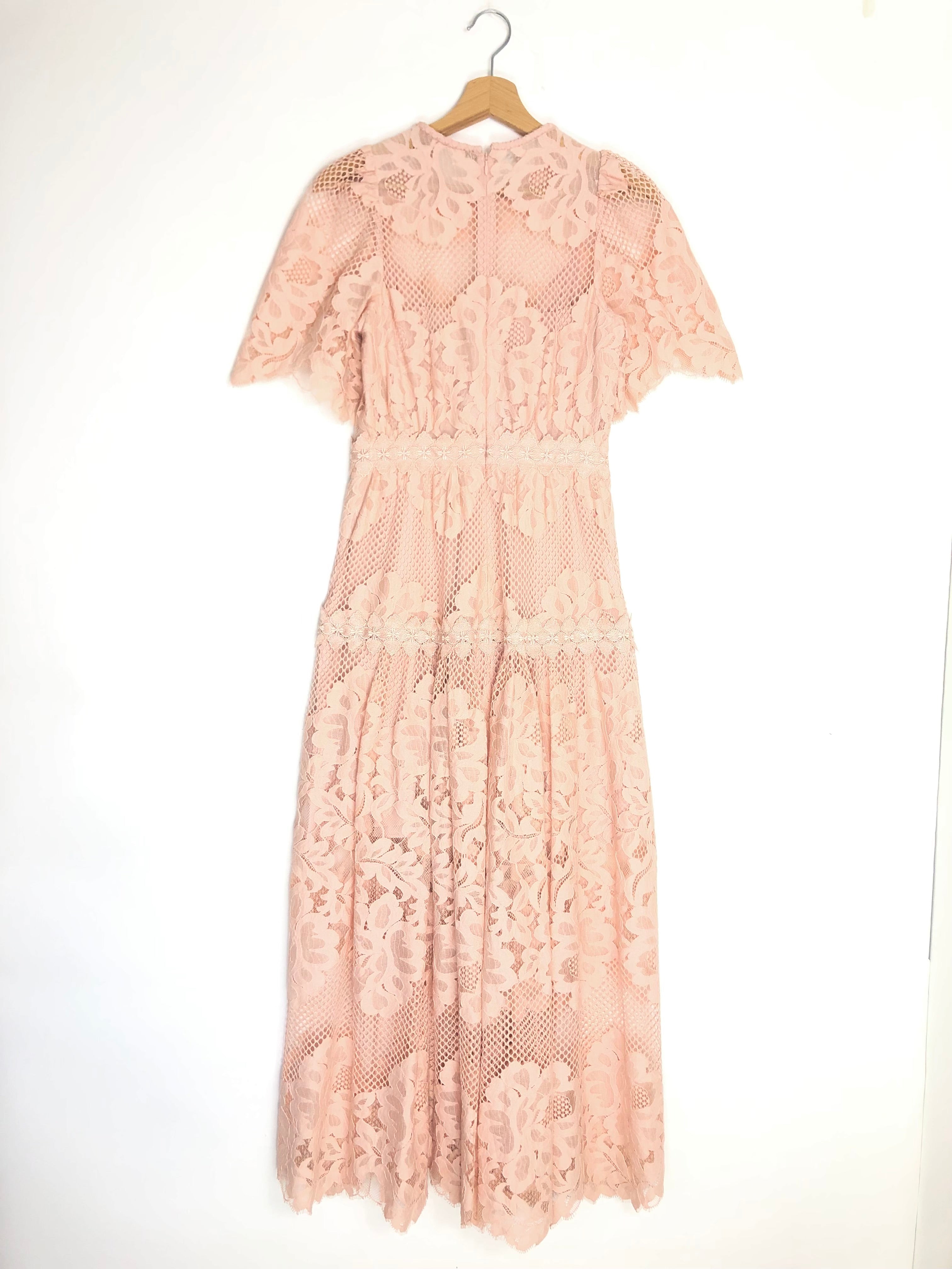 Pink lace dress on a hanger against a white background