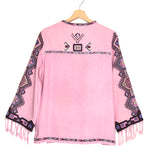 Pink poncho with patterned sleeves and fringes on a hanger against a white background