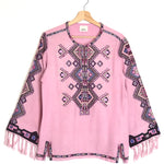 Pink poncho with geometric pattern and fringes on a white background