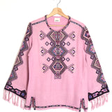 Pink poncho with geometric pattern and fringes on a white background