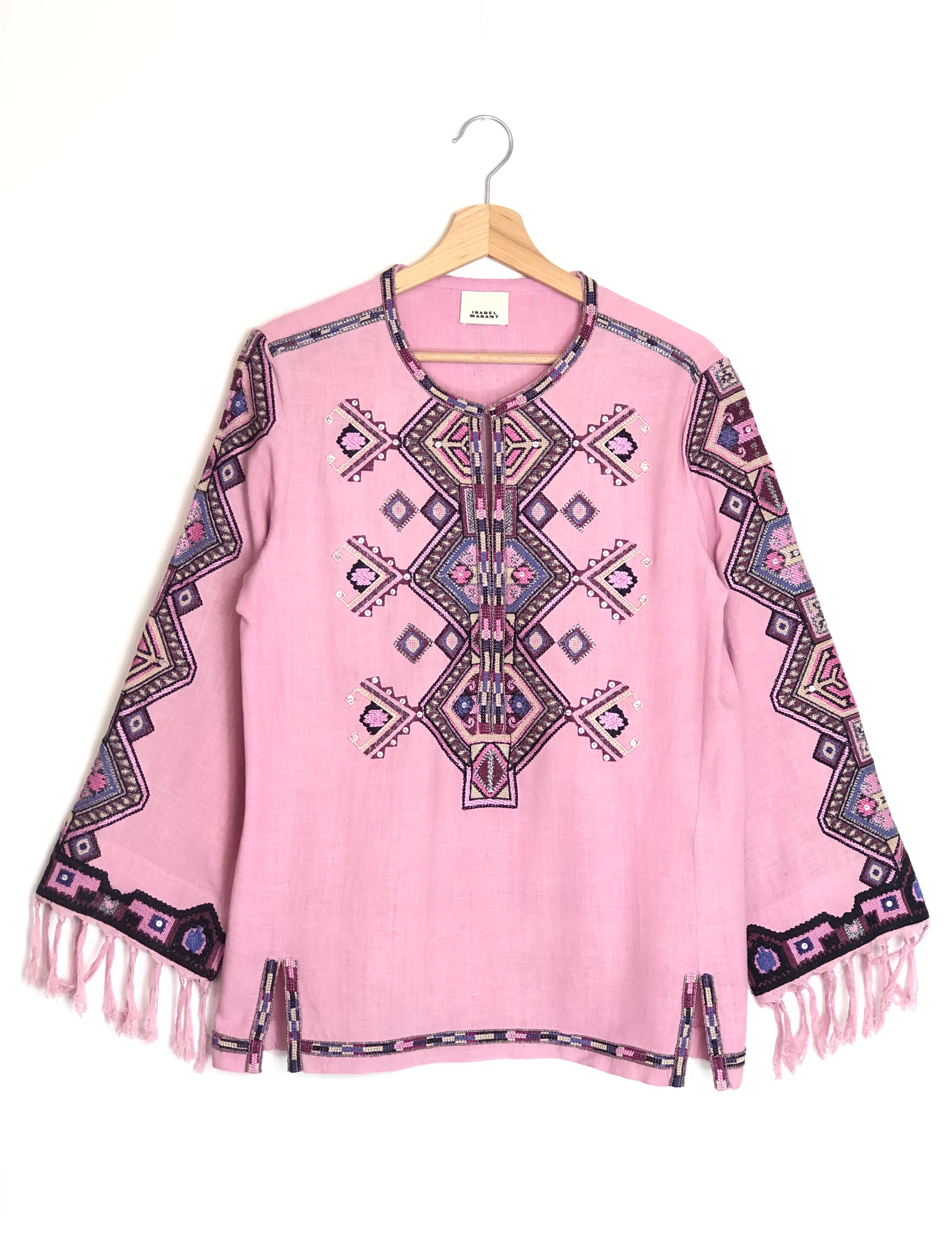 Pink poncho with geometric pattern and fringes on a white background