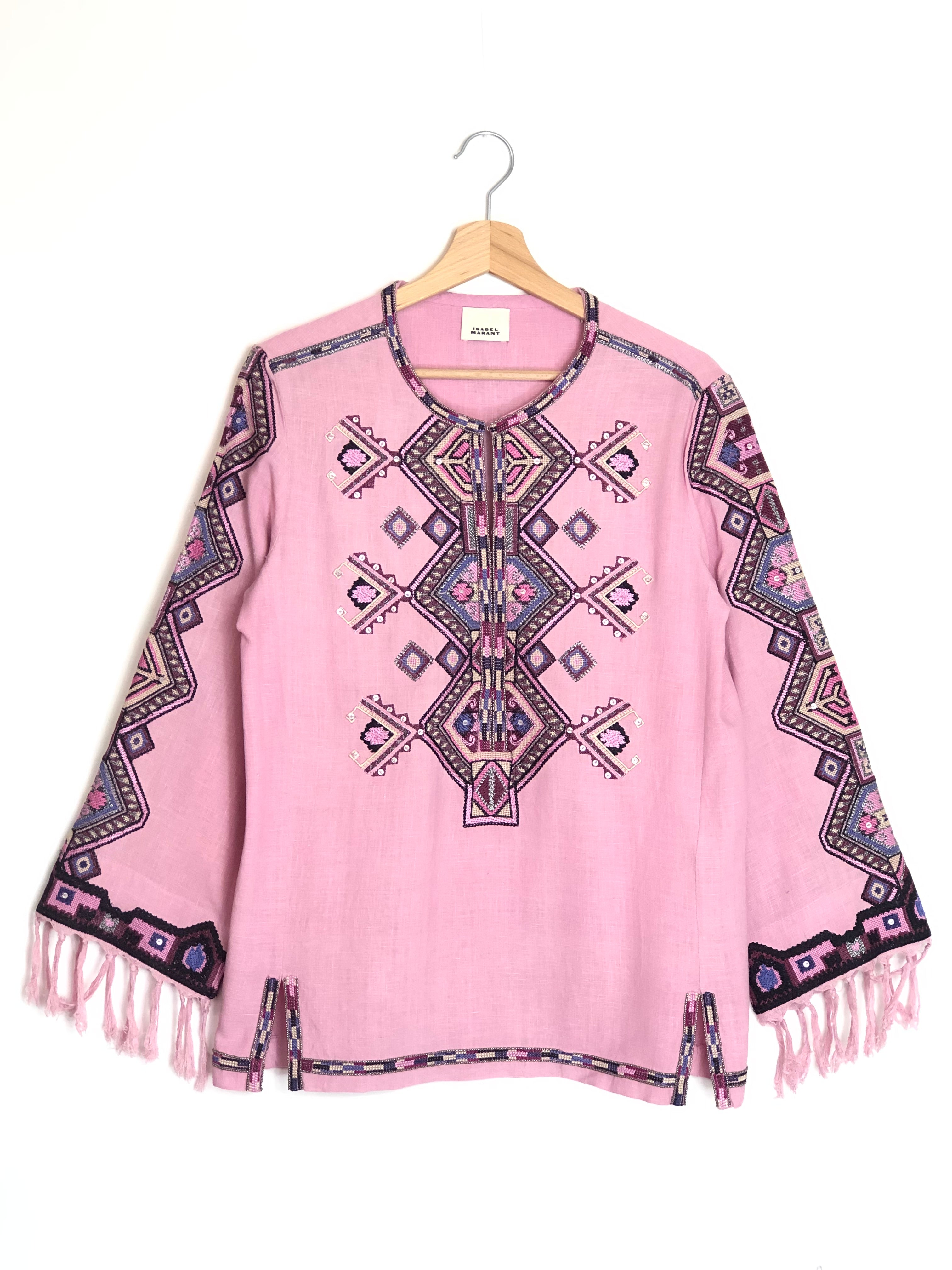 Pink poncho with geometric pattern and fringes on a white background