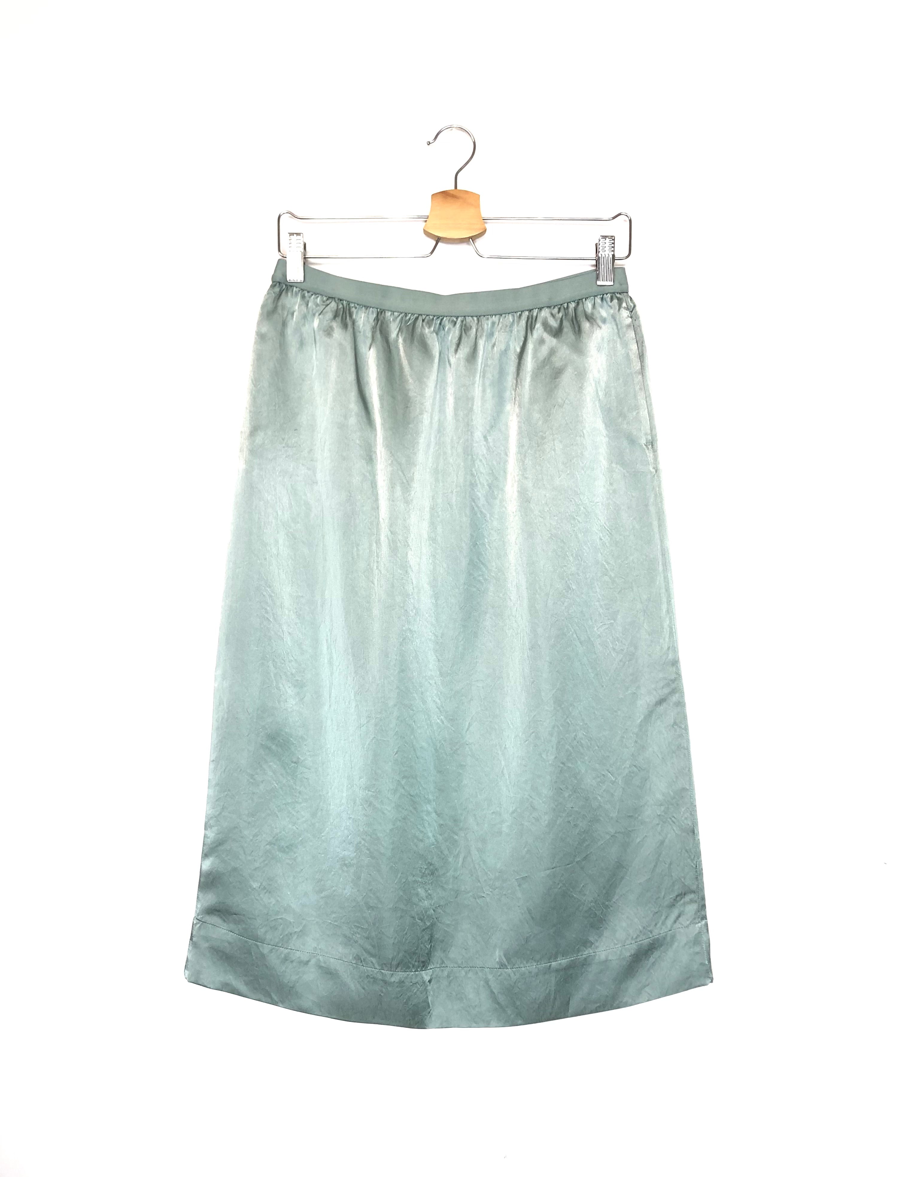 Light green satin skirt on a hanger against a white background