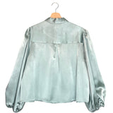 Rain-blue blouse on a hanger against a white background