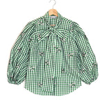 Green checkered shirt with a bow on a white background