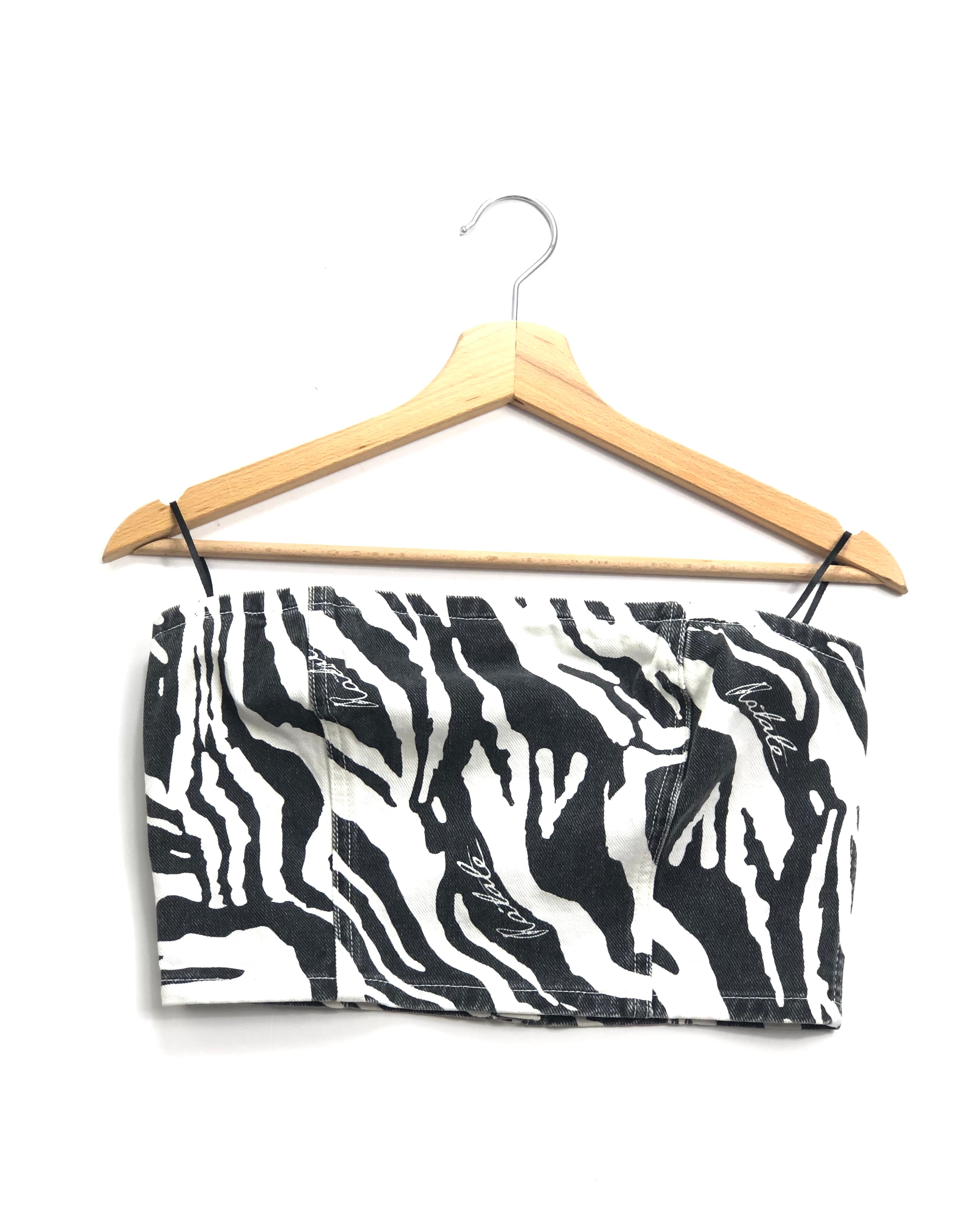 Black and white zebra print top on a wooden hanger against a white background